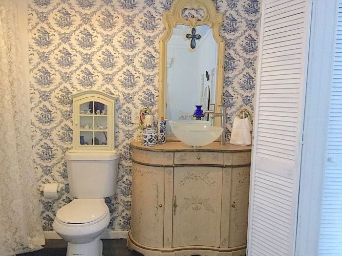 Старинный туалетный столик приспособили под рукомойник, а деревянной перегородкой отделили ванную с санузлом от жилой зоны. | Фото: fanpage.gr.